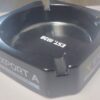 Export A Black Ashtray with sleek matte finish and embossed logo, placed on a wooden tabletop."