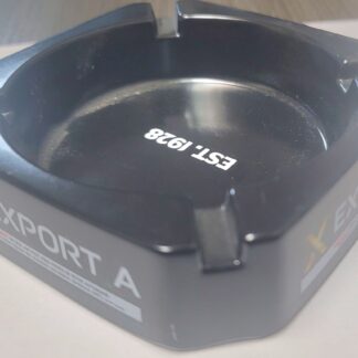 Export A Black Ashtray with sleek matte finish and embossed logo, placed on a wooden tabletop.