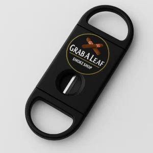 Black V-cut cigar cutter featuring the Grab A Leaf Smoke Shop logo with crossed cigars, shown on a light gray surface with stainless steel V-blade exposed.